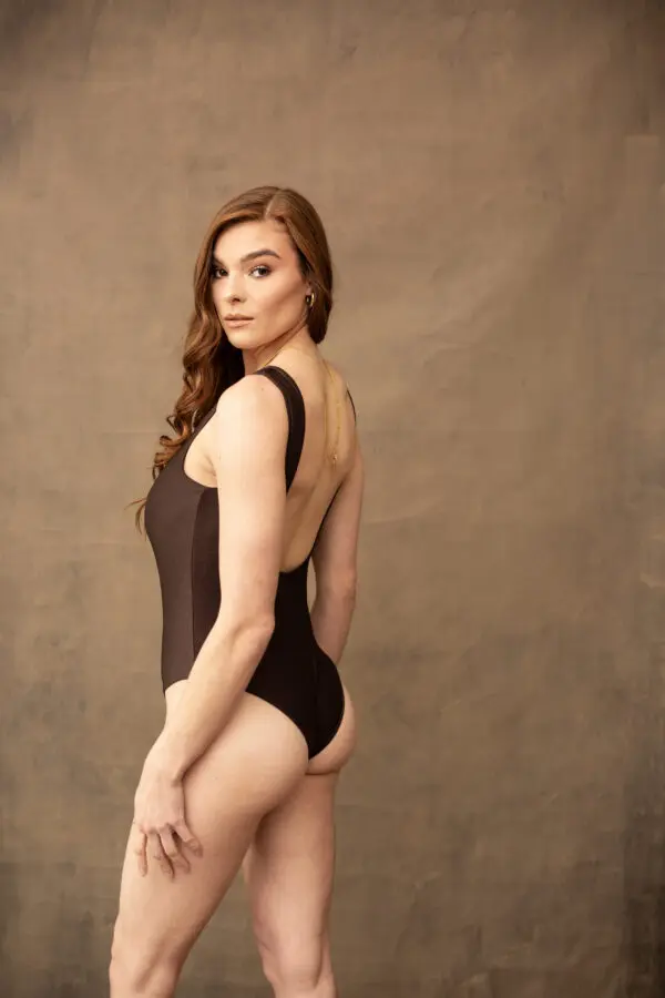 A woman in a black bathing suit poses for the camera.